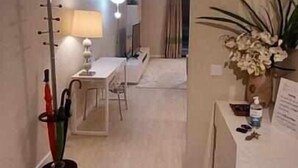 Een moderne, goed verlichte hal met een eetgedeelte, inclusief een tafel en stoelen. Een lamp en een plantje zijn aan de rechterkant zichtbaar.