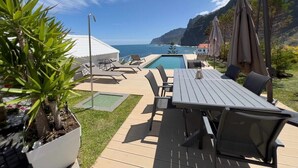 Ein Poolbereich mit Tisch und Stühlen, einem kleinen Pool und Blick auf den Ozean.
