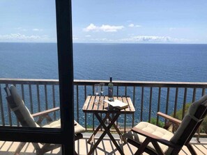 A balcony with a table and chairs overlooking the sea. - Cliff View III - Sea View + Wifi (Funchal)