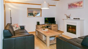 A living room with a fireplace, a television, and a sofa. - 3 bedroom gorgeous home in IJhorst (IJhorst)