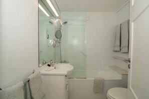 Bathroom features a glass-enclosed shower, sink, toilet, and bathtub.
