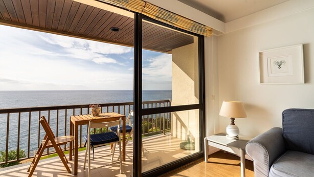 Ein Balkon mit Holztisch und -stühlen, einer Couch und einer Lampe.