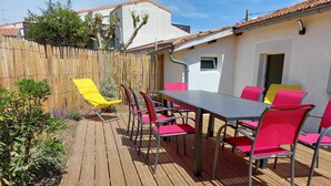 Une terrasse en bois avec une table et des chaises, une chaise jaune et une clôture en bois.