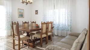 Un comedor con una mesa y sillas de madera, un sofá y una araña.