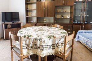 Ein Essbereich mit einem runden Tisch, Stühlen, einem Fernseher und Holzschränken mit Glastüren.