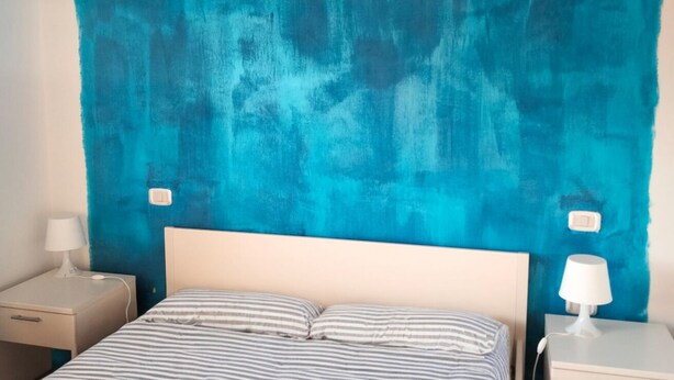 Una habitación con una cama, dos mesitas de noche y una pared azul grande.