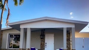 A modern house with a stone facade, a front porch with two white chairs, and a white door. - Dream Vacation House 4B/2B Miami, FL (Hialeah)