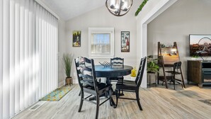 A dining area with a round table, black chairs, and a chandelier. There are potted plants and artwork on the walls. - The Happy Place: 3BR in Quiet Neighborhood (Douglasville)
