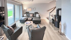 A modern living room with a sectional sofa, a round coffee table, and a fireplace. - Stunning home in Büsum with sauna (Büsum)