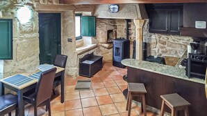 A rustic kitchen with stone walls, a built-in stove, and a bar area with stools. - Lovely home in Muros with WiFi (Muros)