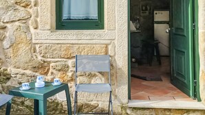 A stone building with a green door, a small table with cups, and a chair. - Lovely home in Muros with WiFi (Muros)