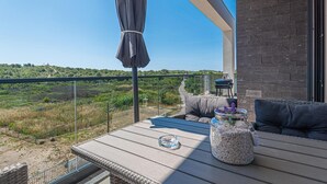 Ein Balkon mit Blick auf eine hügelige Landschaft, ein Glas mit Saatgut und ein Grill.