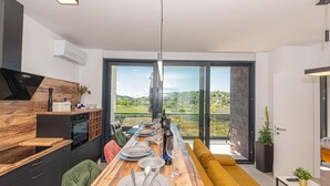 Eine moderne Küche mit Holzarbeitsplatte, ein Essbereich mit gelber Couch und ein großes Fenster mit herrlicher Aussicht.
