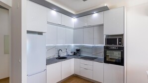 A modern kitchen with white cabinets, a black sink, a coffee maker, a microwave, and an oven. - Stunning apartment in Komarna with WiFi (Komarna)