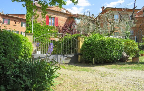 Un quartier résidentiel doté d’une entrée sécurisée par un portail, d’un mur en pierre et d’un immeuble aux volets rouges.