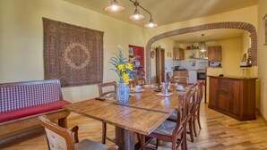 Un coin repas avec une table en bois, des chaises, un vase de fleurs et un banc rouge.