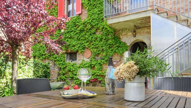 Une table en bois sur laquelle se trouvent un saladier rempli de fraises, un verre à vin et une plante en pot.