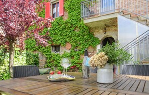 Une table en bois sur laquelle se trouvent un saladier rempli de fraises, un verre à vin et une plante en pot.