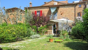 Une cour avec un chemin en pierre, des plantes en pot et un petit espace aménagé pour s’asseoir à l’extérieur.