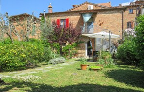 A courtyard with a stone pathway, potted plants, and a small outdoor seating area.