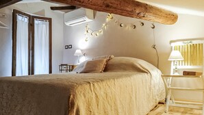 Une chambre dotée d’un grand lit, d’un appareil de climatisation, d’un plafond avec poutres apparentes et d’une guirlande lumineuse.