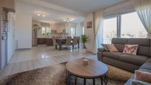 Un apartamento moderno con sala de estar, comedor y cocina. Se observa un sofá, una mesa de comedor y una encimera de cocina.