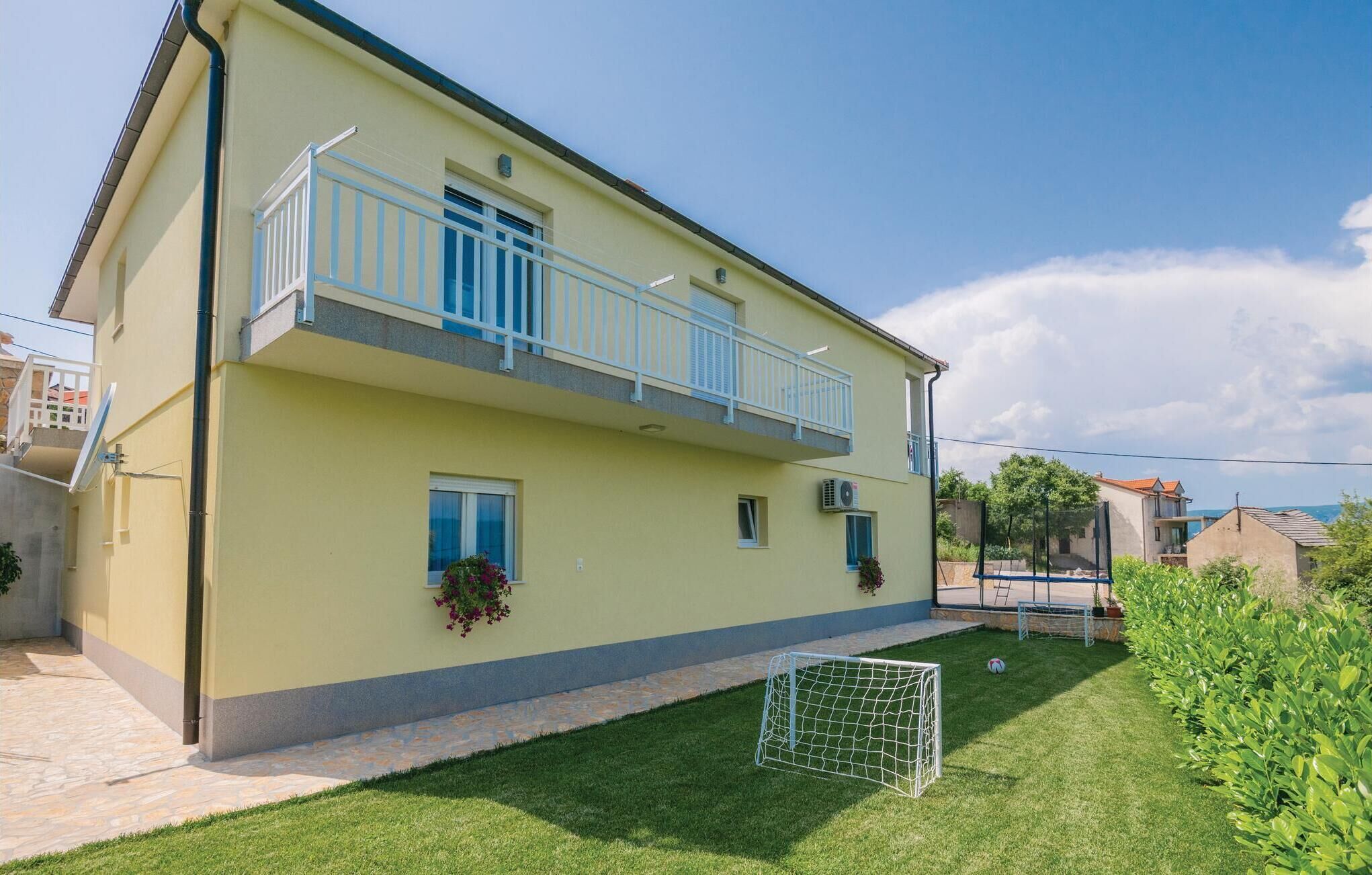 A two-story building with a balcony, a small garden, and a soccer goal.