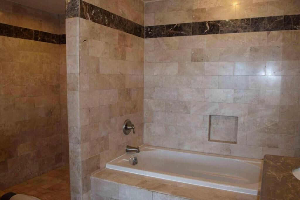 Une salle de bain avec une baignoire, des carreaux de marbre et un petit tableau encadré au mur.
