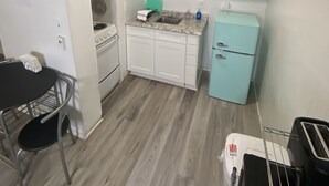 A compact kitchen with white cabinets, a sink, a stove, and a small refrigerator. - Uptown Suites (St. Petersburg)