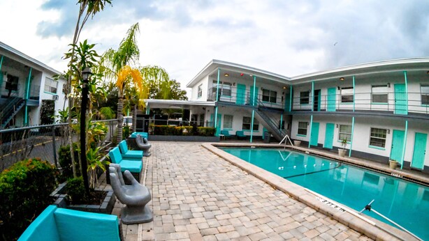 A swimming pool area with a tiled deck, benches, and a staircase leading to an upper level. - Uptown Suites (St. Petersburg)