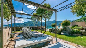 Un espace extérieur abrité, aménagé avec des sièges, et offrant une vue sur les montagnes et une piscine.