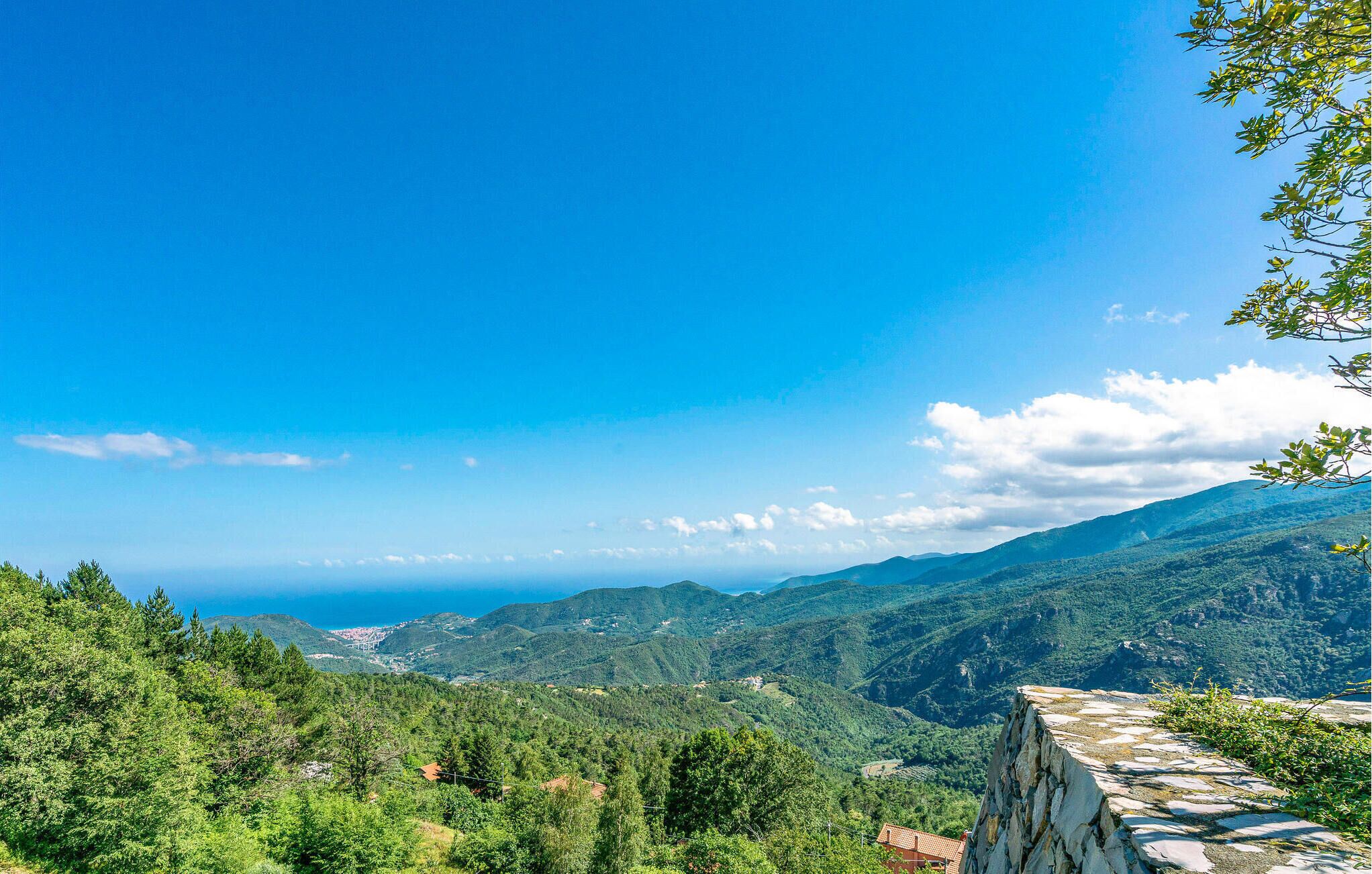 A mountainous landscape with a clear sky and a distant view of the sea.