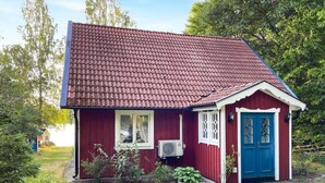 A small, red wooden house with a blue door and white-framed windows, surrounded by greenery. - Stunning home in Eringsboda with sauna (Eringsboda)