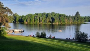 Blick auf einen See mit einer Anlegestelle, Stühlen und einer Rasenfläche.
