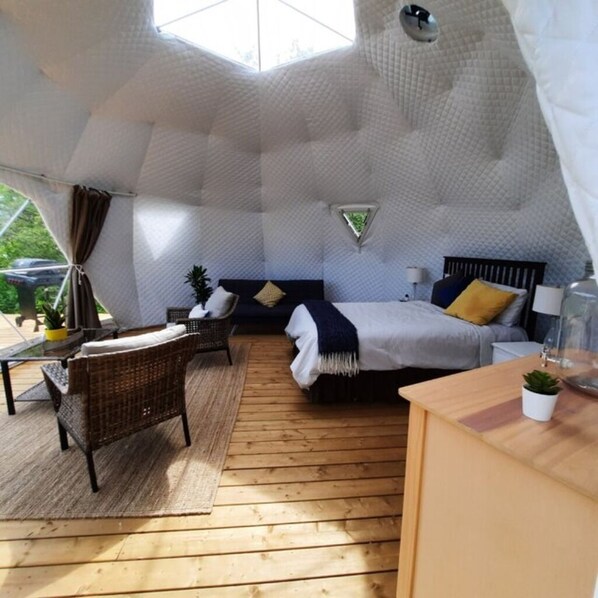 Une pièce confortable, à la forme originale, comprenant un lit, un coin salon et une petite table.