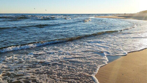 A beach with waves, a pier, and a clear sky. - Nice apartment in Jaroslawiec with WiFi (Jaroslawiec)