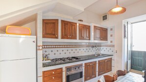 A kitchen with wooden cabinets, a gas stove, an oven, and a refrigerator. - Cozy home in Sampieri with WiFi (Sampieri)