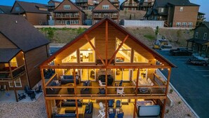 Una cabaña de varios pisos con chimenea central, asientos al aire libre y vistas del entorno.