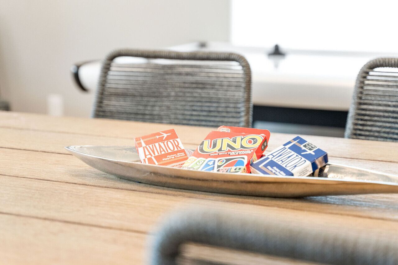 Une table à manger sur laquelle se trouve un plateau en métal contenant des jeux de cartes UNO et Aviator.