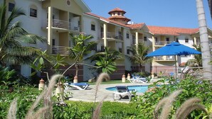 A hotel with multiple balconies, a swimming pool, and palm trees. - Peaceful Studio in Ocean Dream (Cabarete)