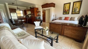 A living room with a sofa, coffee table, and a dining area with chairs. There is a kitchen visible in the background. - Peaceful Studio in Ocean Dream (Cabarete)