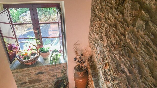 Paredes de pedra e uma janela com plantas em vasos.