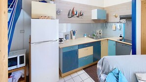 A compact kitchen with a refrigerator, microwave, and sink.
