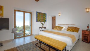 Ein Schlafzimmer mit einem großen Bett, einer Bank, einem Schreibtisch und einem Stuhl.