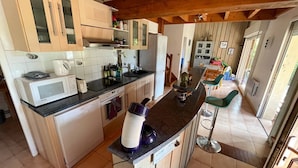 A kitchen with a microwave, toaster, sink, and a blender on the counter.