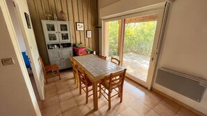 A dining area with a table and chairs, a cabinet with glass doors, and a sliding glass door leading to an outdoor patio.
