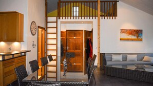 A modern interior with a dining area, a loft bedroom, and a living room.
