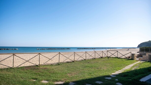 A beach with a wooden fence, grassy area, and a clear blue sky. - Lovely apartment in Ortona with WiFi (Ortona)