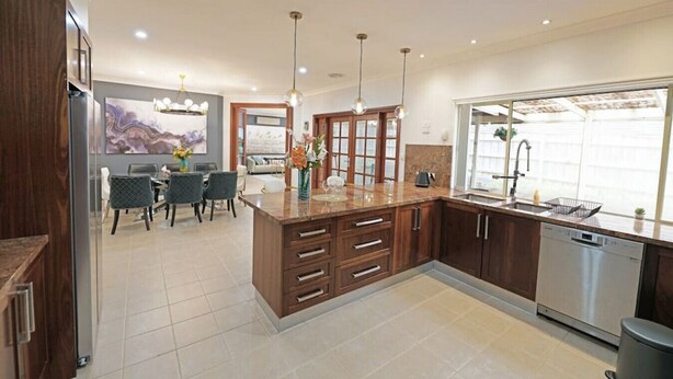 Una cocina moderna con armarios de madera, lavavajillas integrado y un comedor con mesa y sillas.