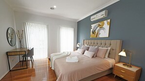 Un dormitorio con una cama grande, mesitas de noche, un escritorio y una silla.